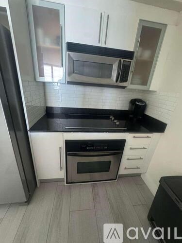 A pool with sun loungers and a view of the water and buildings.