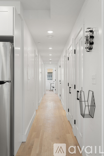 A long hallway with white walls and wood floors.