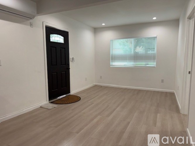 A room with a black door and a window with blinds.