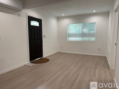 A room with a black door and a window with blinds.