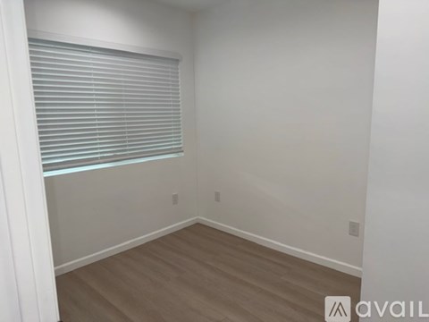 A room with wooden flooring and a window with blinds.