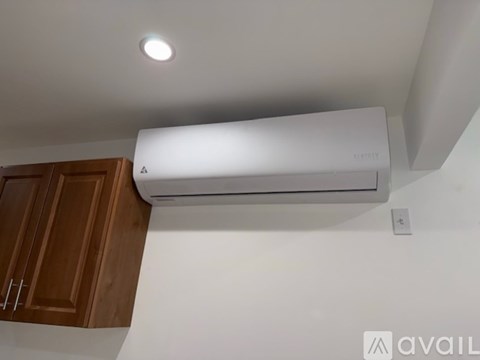 A white air conditioner is mounted on a wall above a wooden cabinet.