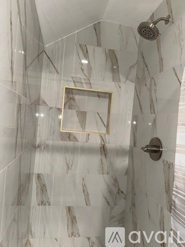 A bathroom with a marble wall and a gold picture frame.