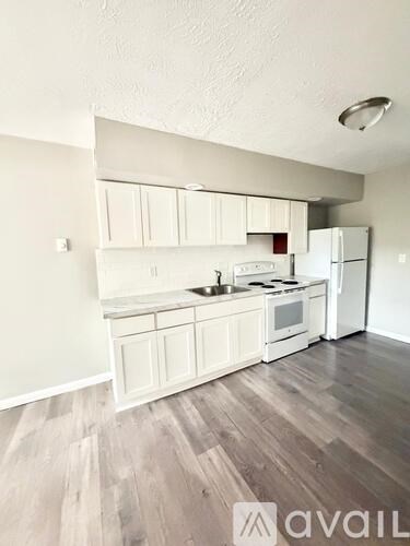 A kitchen with white cabinets and a wooden floor.