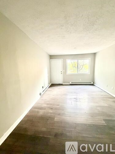 A room with wooden flooring and a door leading to a balcony.