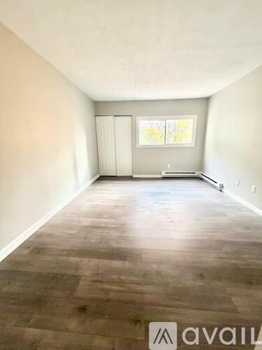 A room with wooden flooring and a window with a white frame.