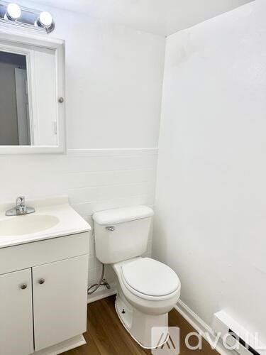 A white toilet sits next to a white sink in a small bathroom.