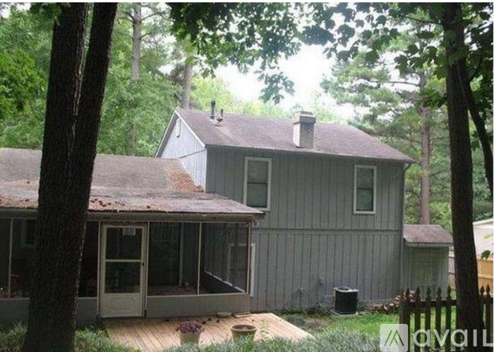 A house with a grey siding and a brown roof is surrounded by trees.