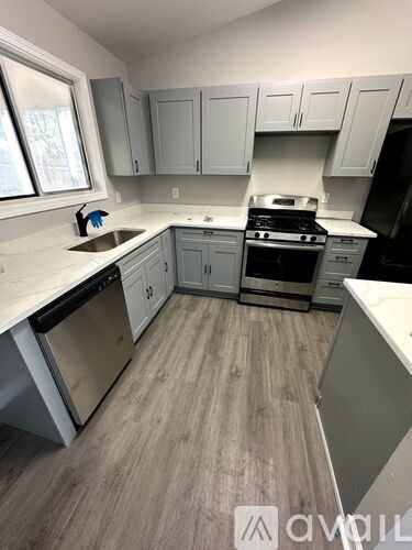 A kitchen with a white counter top and grey cabinets.