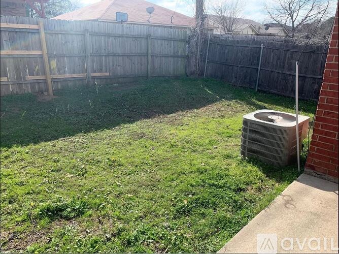 A backyard with a fence and a small air conditioning unit.