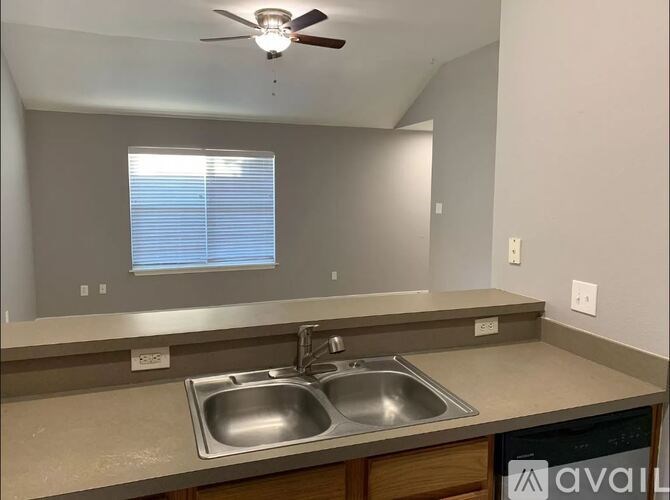 A kitchen with a stainless steel sink and a ceiling fan.