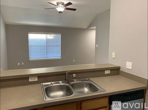 A kitchen with a stainless steel sink and a ceiling fan.