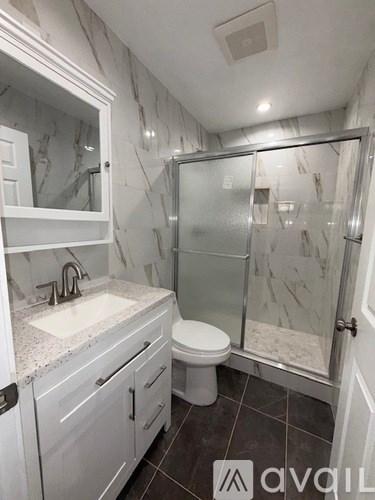 A bathroom with a marble wall and a walk-in shower.