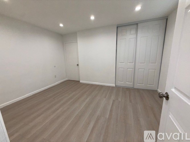 A room with a white door and a wooden floor.