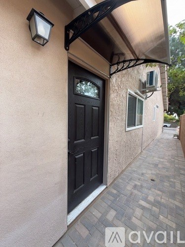 A black door is on the left side of a tan wall.