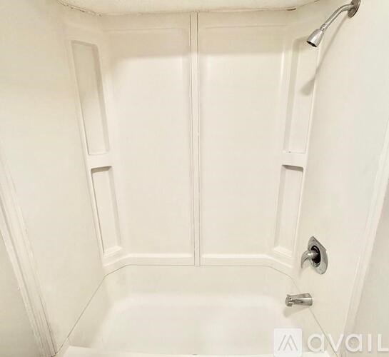 A white bathroom with a tub and a shower head.