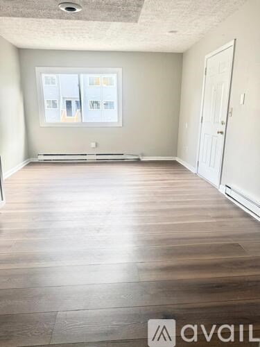 A room with wooden flooring and a large window.