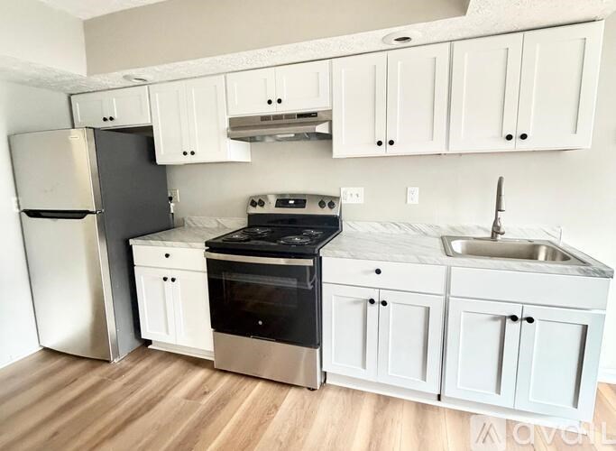 A kitchen with white cabinets and a black stove top oven.