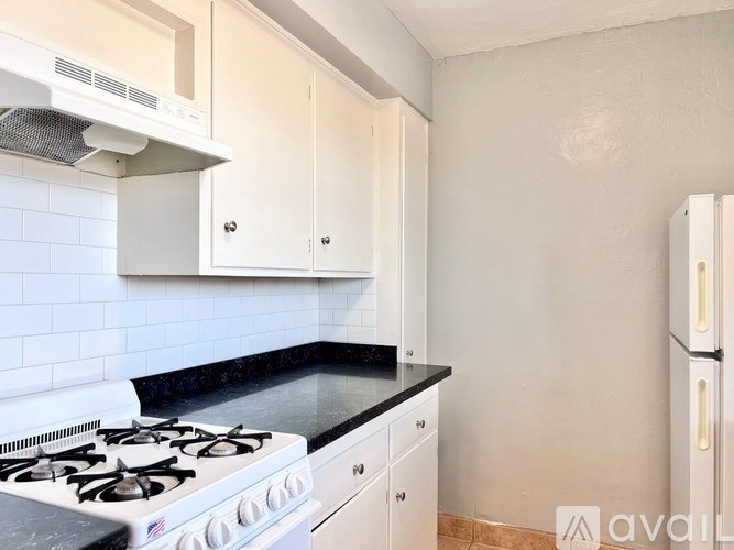 A kitchen with a white stove and cabinets.