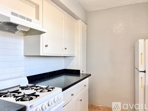 A kitchen with a white stove and cabinets.