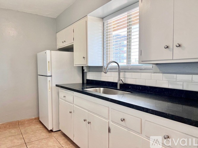 A kitchen with white cabinets and a black countertop.