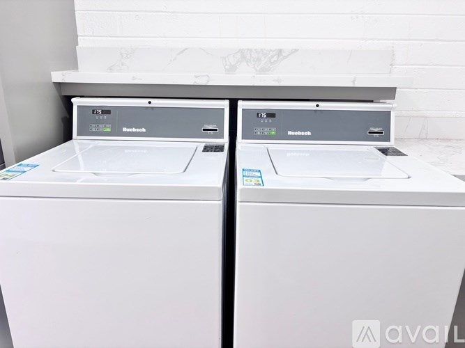 Two white front loading washing machines are side by side.