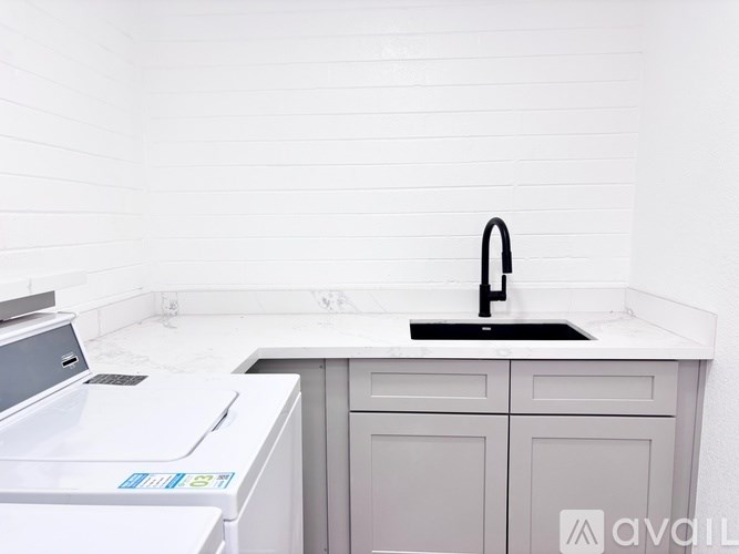 A modern kitchen with a white washing machine and a black faucet.