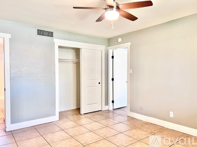 A room with a ceiling fan and a white door.