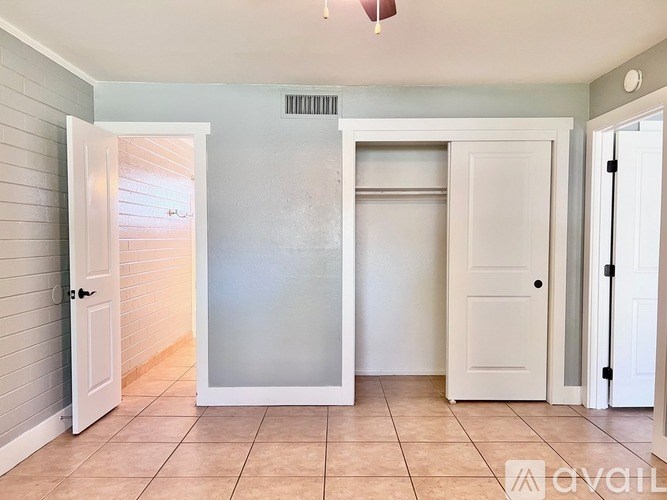 A room with a white door, a window, and a tiled floor.