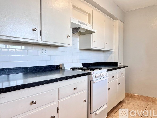 A kitchen with white cabinets and a black countertop.