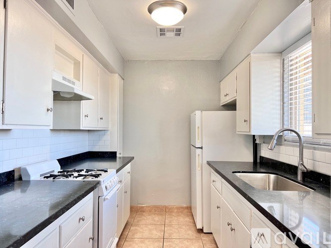 A kitchen with white cabinets and black countertops.