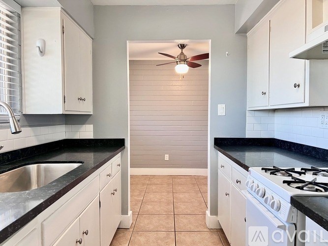 A kitchen with white cabinets and black countertops.