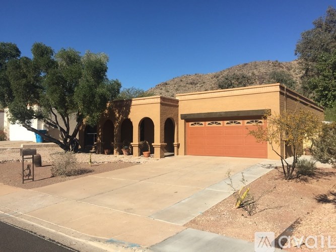 A house with a garage and a tree in front.