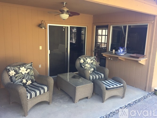 A patio with a chair, a table and a ceiling fan.