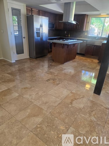 A kitchen with a tile floor and a refrigerator.