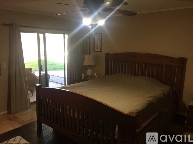 A bedroom with a bed, a ceiling fan, and a sliding glass door.