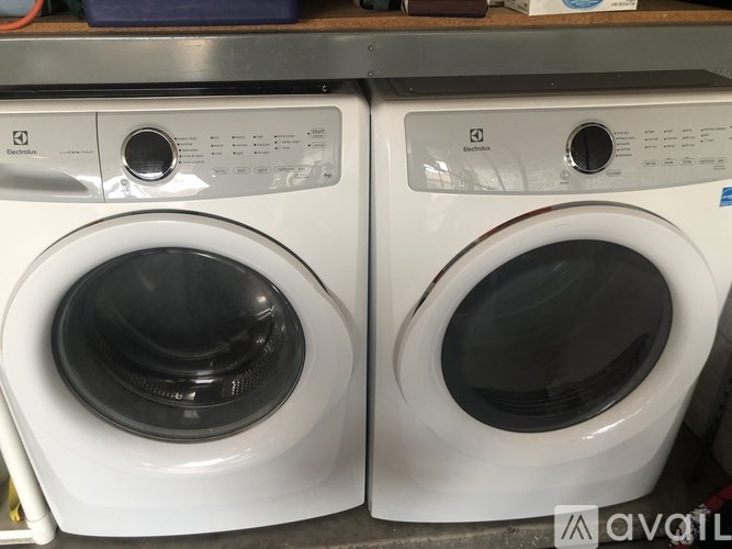 Two white front loading washing machines on a shelf.