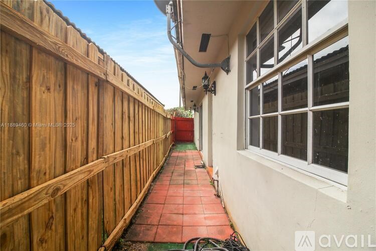 A narrow alley with a wooden fence on the left and a red tiled floor.