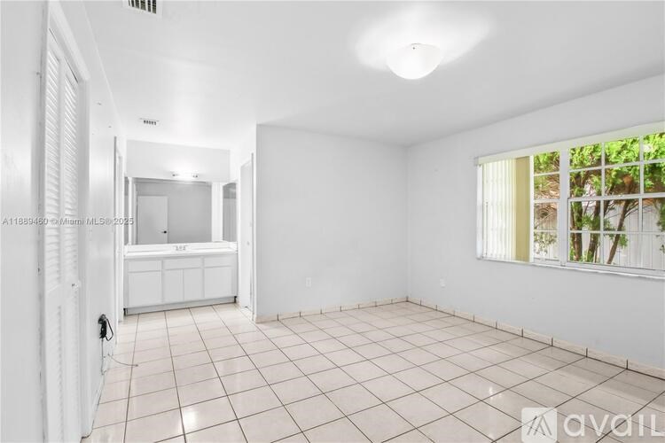 A white room with a tiled floor and a window with a view of trees outside.