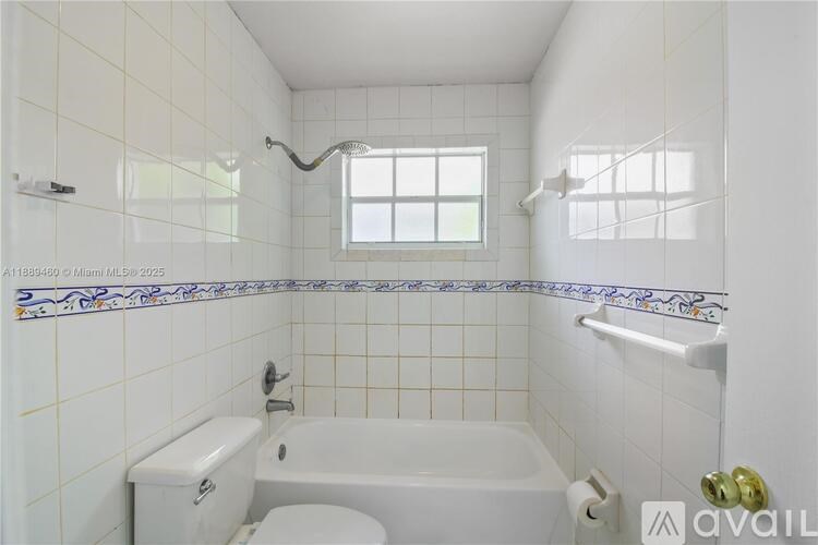A white bathroom with a tub, toilet and sink.