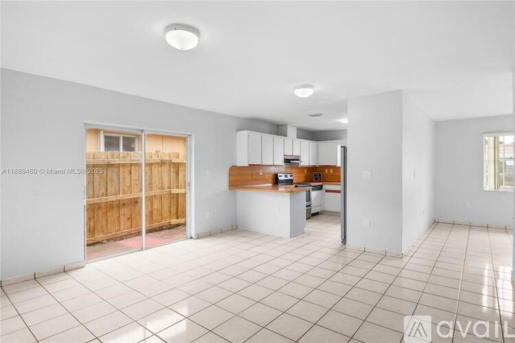 A large, empty room with white walls and a tiled floor.