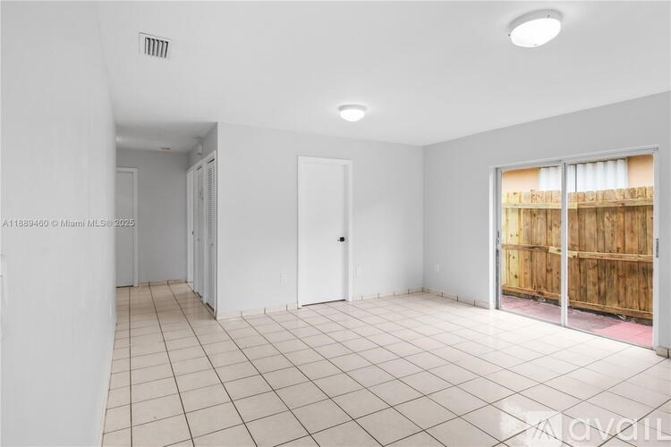 A spacious room with white walls and tiled flooring.