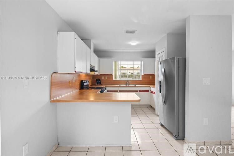 A kitchen with white cabinets and a wooden countertop.