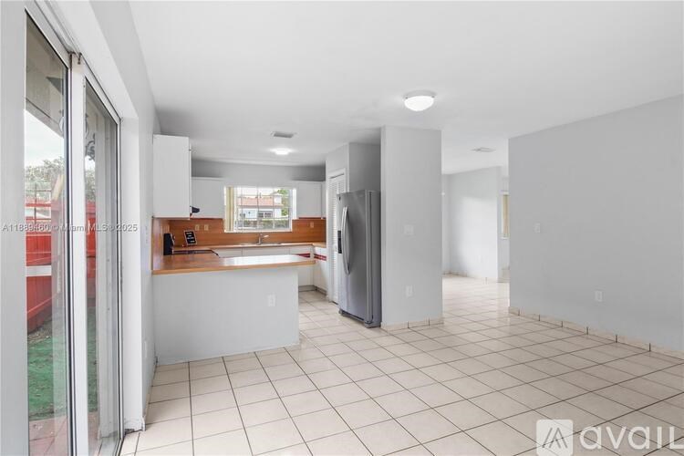 A kitchen with white tiled floors and a refrigerator.