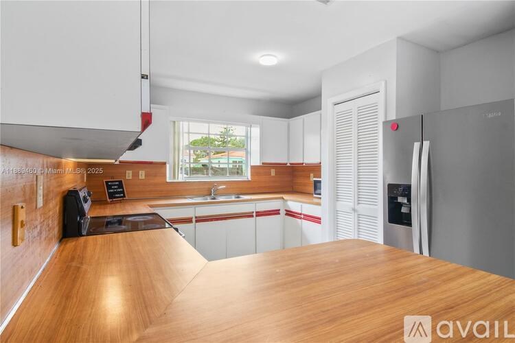A kitchen with a wooden countertop and white cabinets.