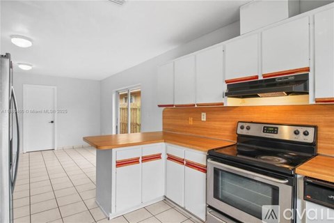 A kitchen with white cabinets and a wooden countertop.