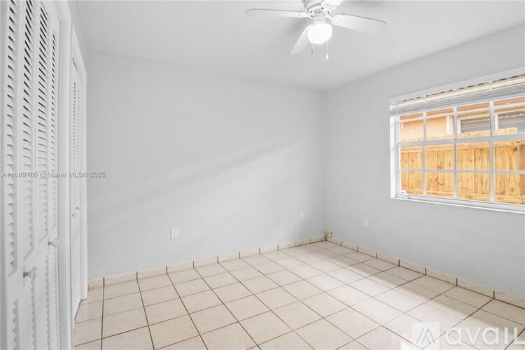 A room with a fan and a window with wooden blinds.