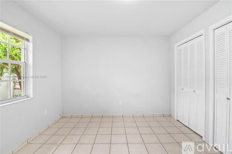 A white room with a window and a white closet.