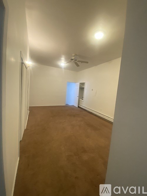 A room with brown carpet and a ceiling fan.