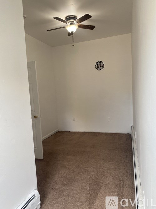 A room with a ceiling fan and carpeted floor.